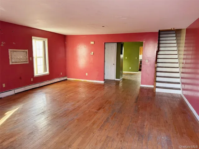 a view of an empty room with window and wooden floor