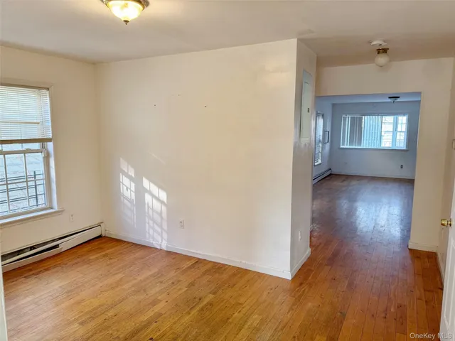 an empty room with wooden floor cabinet and windows