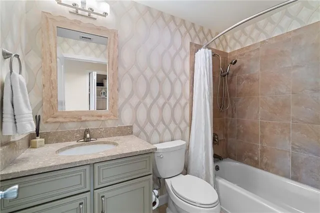 a bathroom with a granite countertop sink a toilet and shower