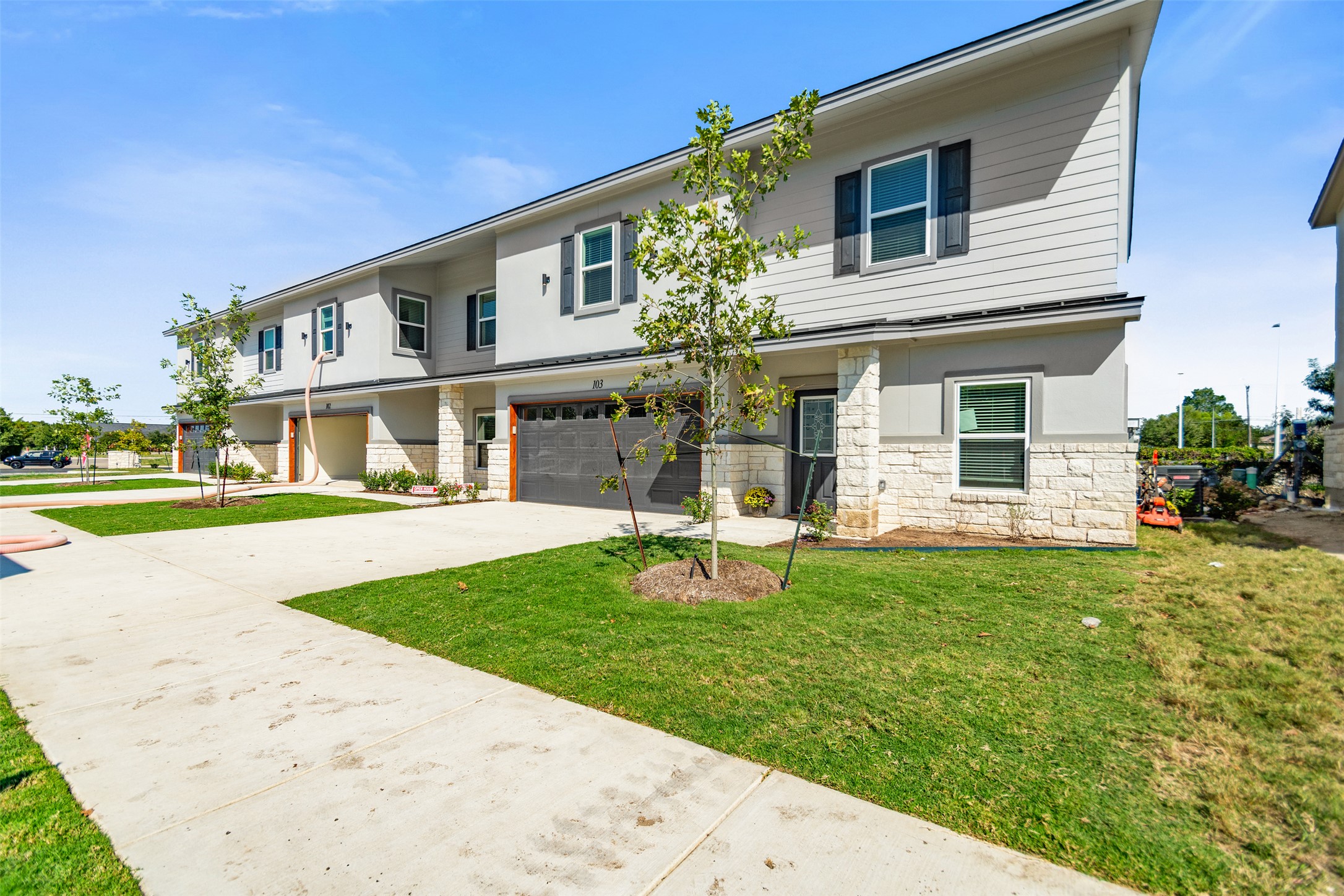 2105 Tiger Trail, Unit 103 Round Rock, TX 78664 - Photo 5 of 38 View of front facade with stone siding, driveway, a garage, and a front lawn