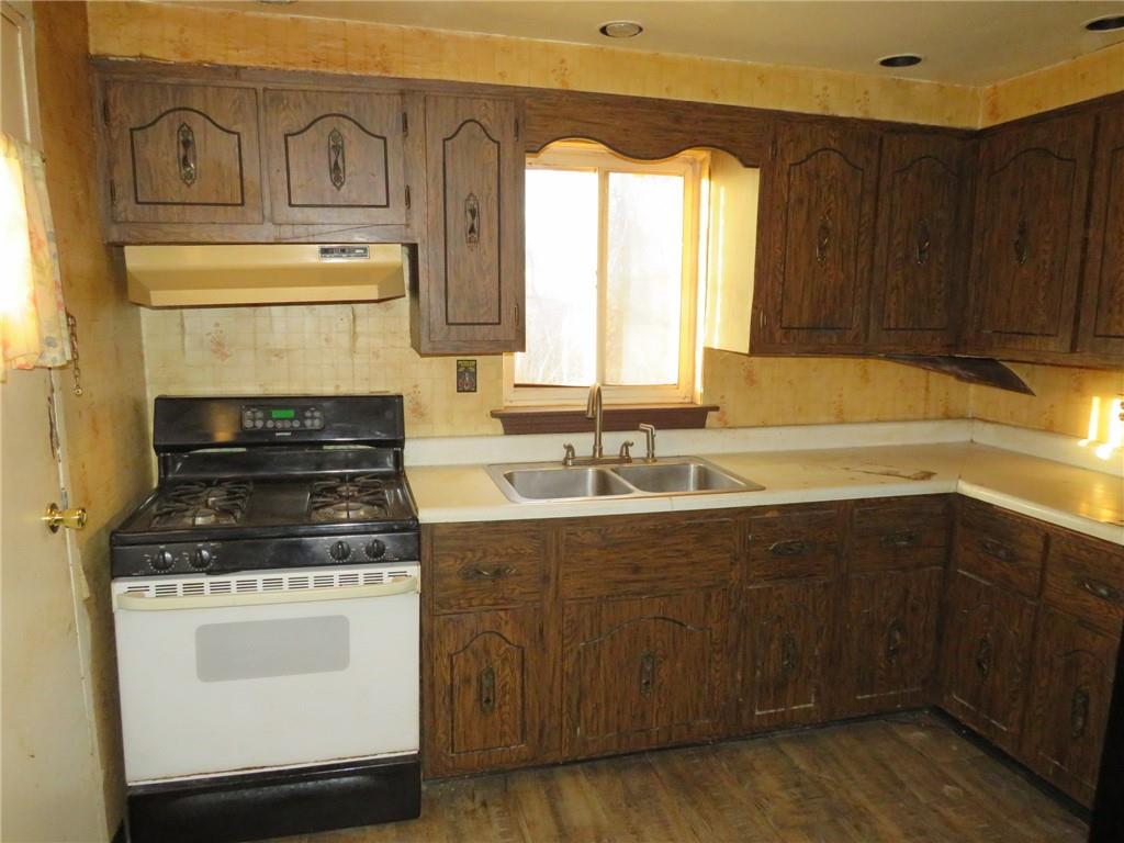 1252 Brinton Road Pittsburgh, PA 15221 - Photo 15 of 35 a kitchen with granite countertop a stove a sink and dishwasher with wooden cabinets