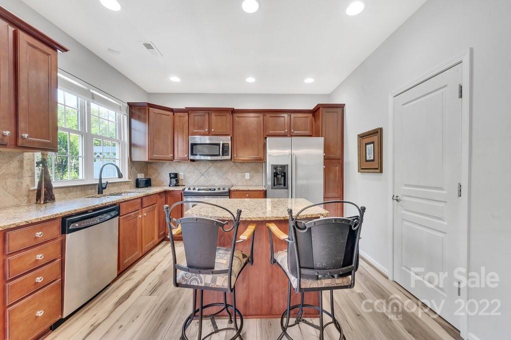 584 6th Baxter Crossing Fort Mill, SC 29708 - Photo 8 of 21 a kitchen with stainless steel appliances granite countertop a stove top oven a sink dishwasher a dining table and chairs with wooden floor