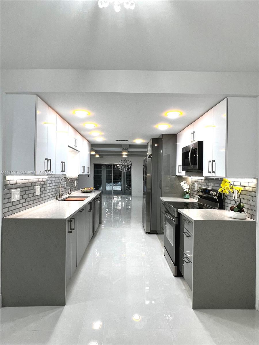 a kitchen with stainless steel appliances kitchen island granite countertop a sink and a stove top oven