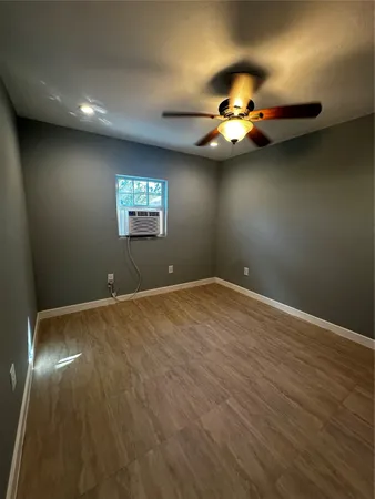 an empty room with windows and fan