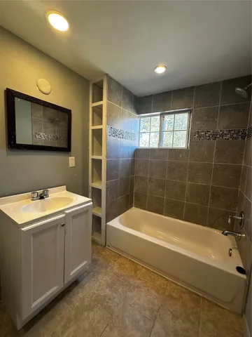 a bathroom with a tub a sink and mirror