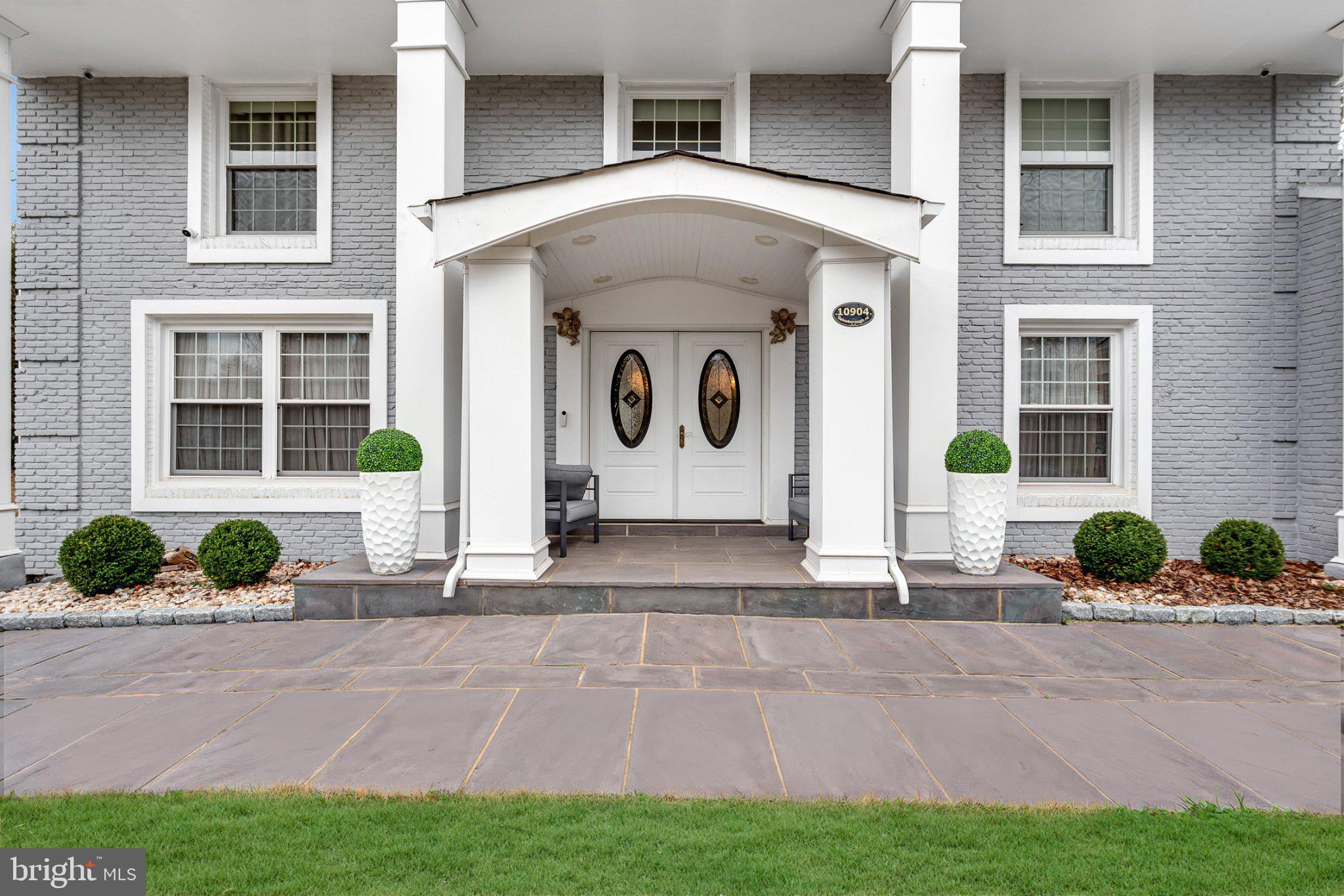 a front view of a house with a yard and potted plants
