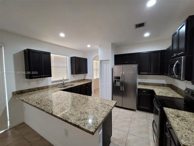 a kitchen with stainless steel appliances granite countertop a sink refrigerator and microwave