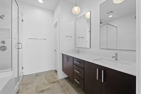 a spacious bathroom with a double vanity sink a mirror and a shower