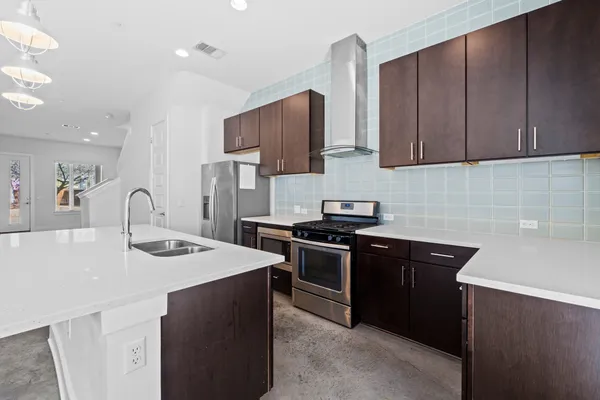 a kitchen with stainless steel appliances granite countertop a sink stove and refrigerator
