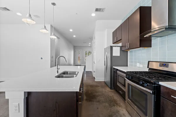 a kitchen with kitchen island stainless steel appliances a sink stove and refrigerator