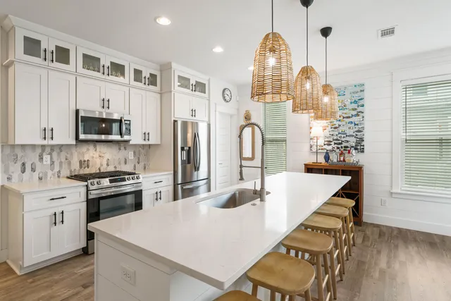 a kitchen with stainless steel appliances kitchen island granite countertop a refrigerator a stove top oven a dining table and chairs with wooden floor