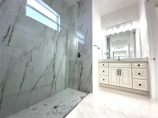 a bathroom with a granite countertop sink a mirror a vanity and a shower