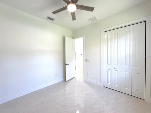 a view of an empty room and chandelier fan
