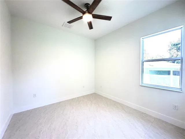 an empty room with a window and a fan