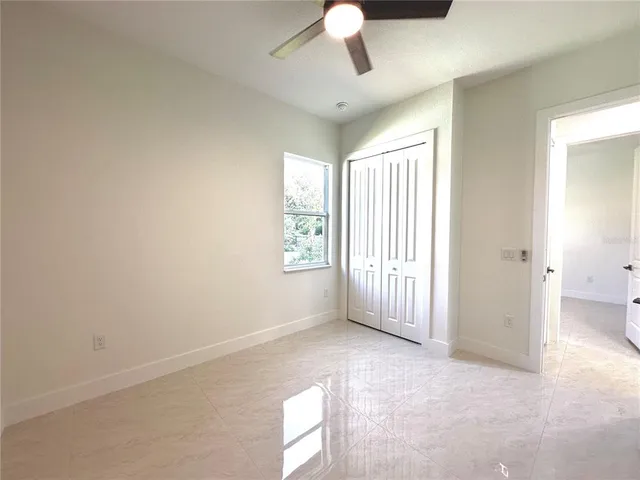 an empty room with chandelier fan and windows