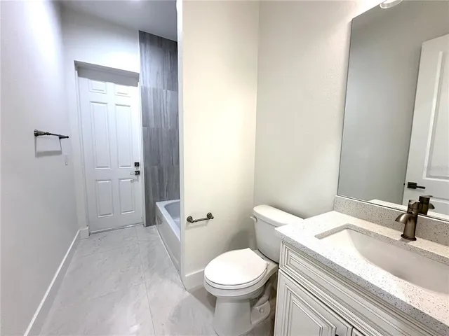 a bathroom with a granite countertop toilet a sink and a mirror