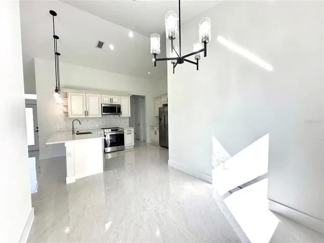 a kitchen with a refrigerator a stove and white cabinets with wooden floor