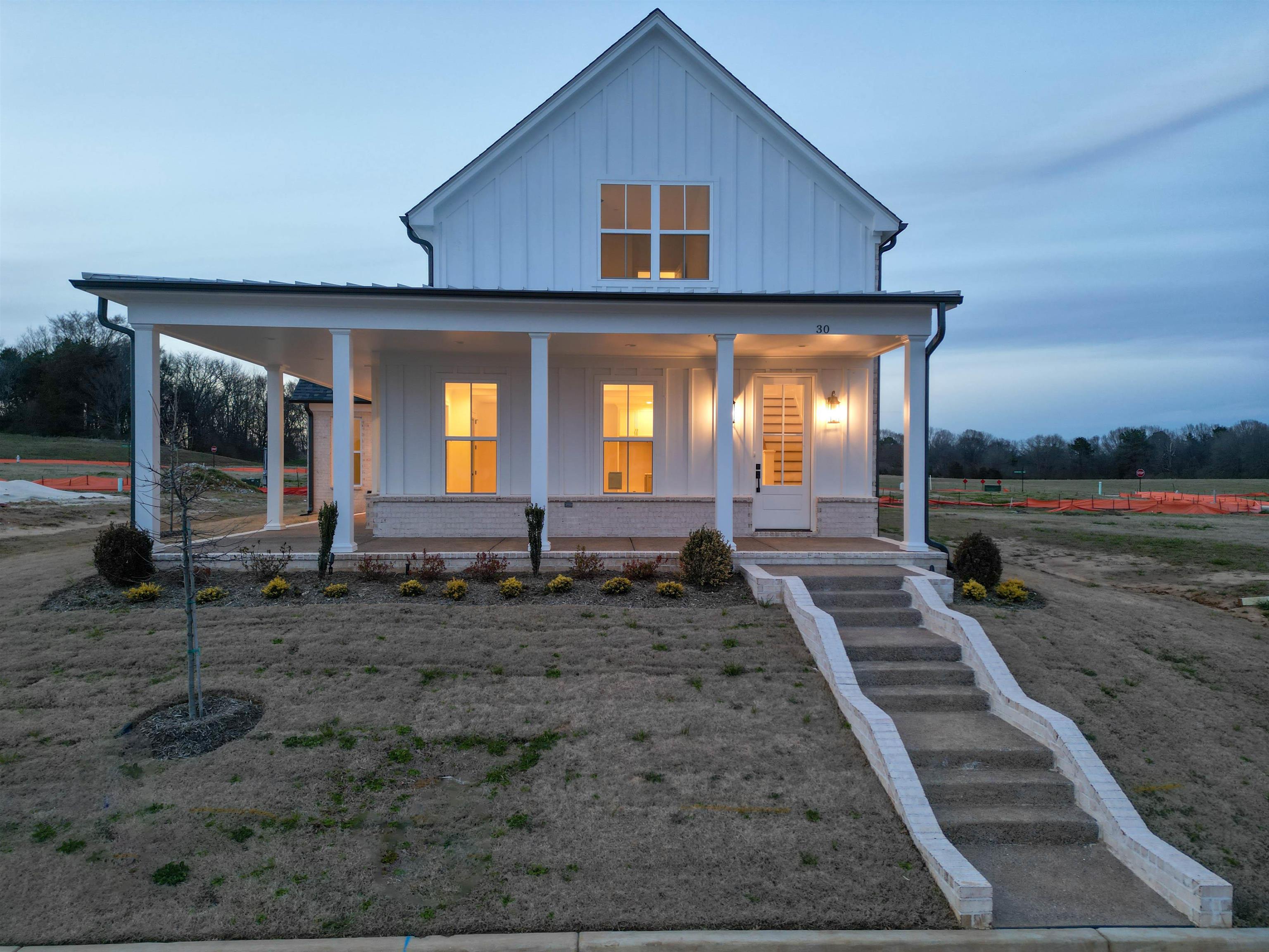 View of front facade with a porch, brick siding, and board and batten siding