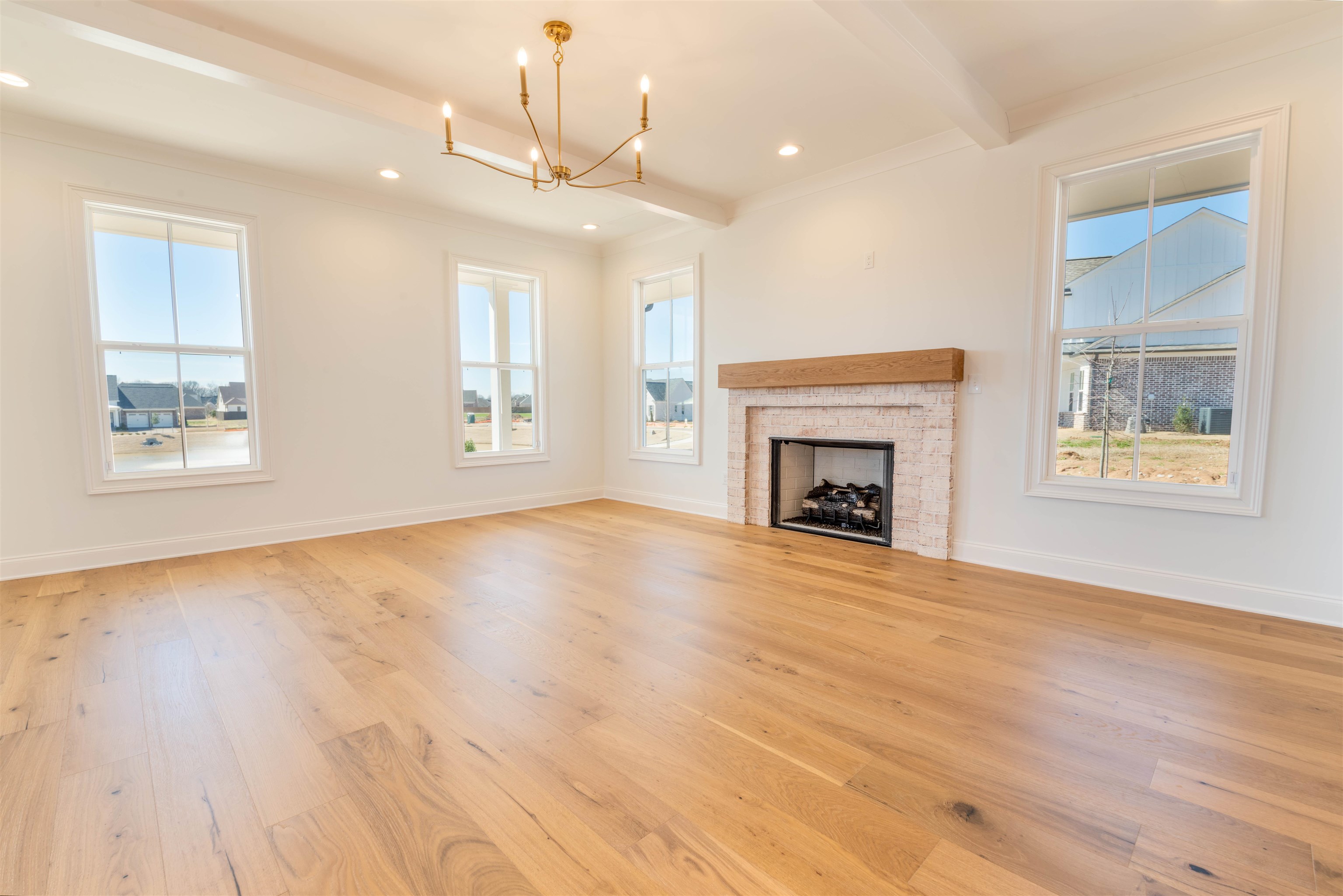 30 Rambling Rex Trail Piperton, TN 38017 - Photo 9 of 25 Unfurnished living room with a fireplace, beamed ceiling, light wood-style flooring, and baseboards