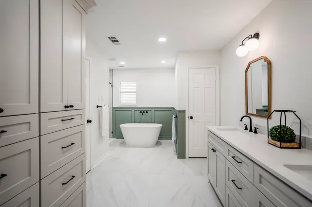 a spacious bathroom with a double vanity sink a mirror and a bathtub