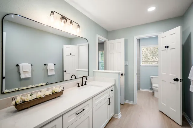 a bathroom with a double vanity sink and mirror with toilet
