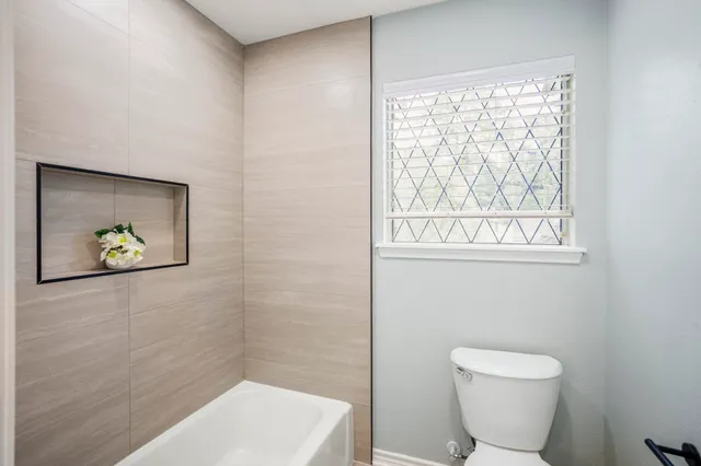 a bathroom with a toilet and a picture on the wall