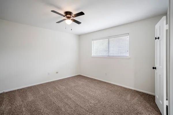 an empty room with a window and a fan