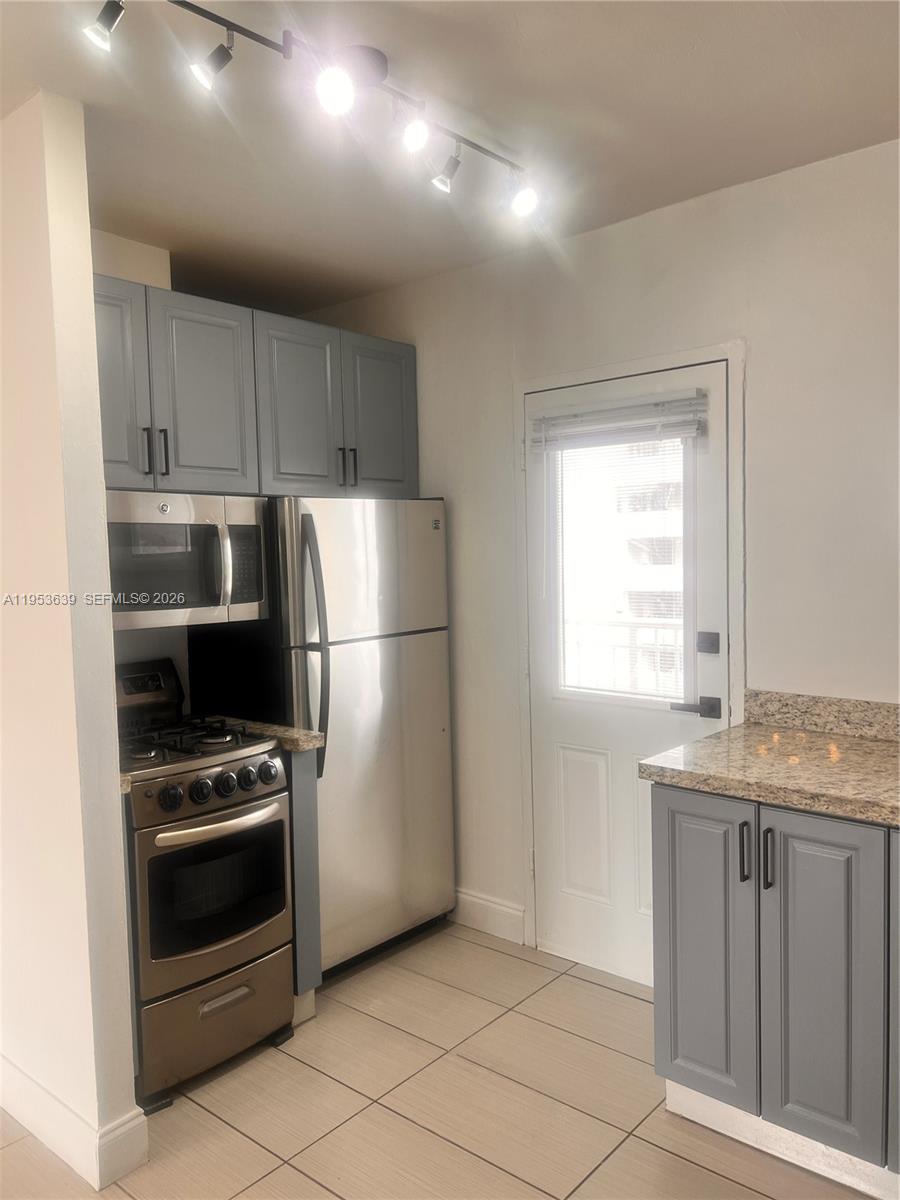 1300 Lincoln Road, Unit B902 Miami Beach, FL 33139 - Photo 7 of 17 a kitchen with granite countertop a refrigerator and a stove top oven