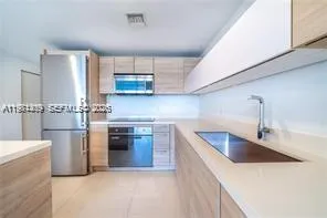 a kitchen with stainless steel appliances granite countertop a sink and a refrigerator