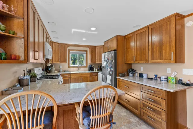 a kitchen with stainless steel appliances granite countertop a sink dishwasher a refrigerator with wooden cabinets and floors