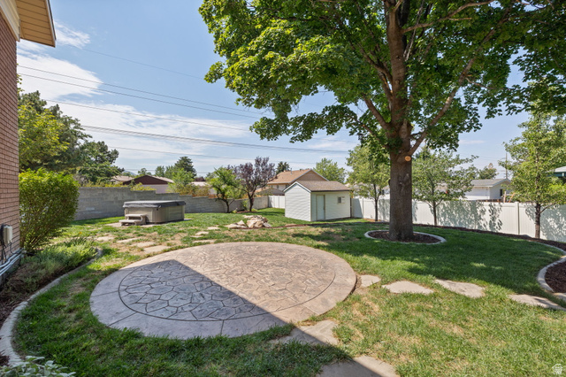 2370 Quail Run Circle East Sandy, UT 84093 - Photo 42 of 54 Spacious backyard featuring a stamped concrete patio, hot tub, mature trees, and a storage shed