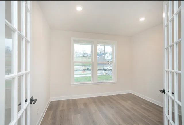 an empty room with wooden floor and windows