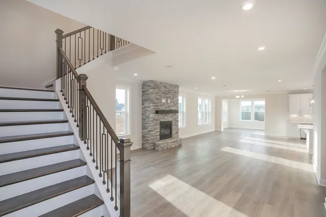 a view of an entryway with wooden floor leading to a furnished livingroom and windows