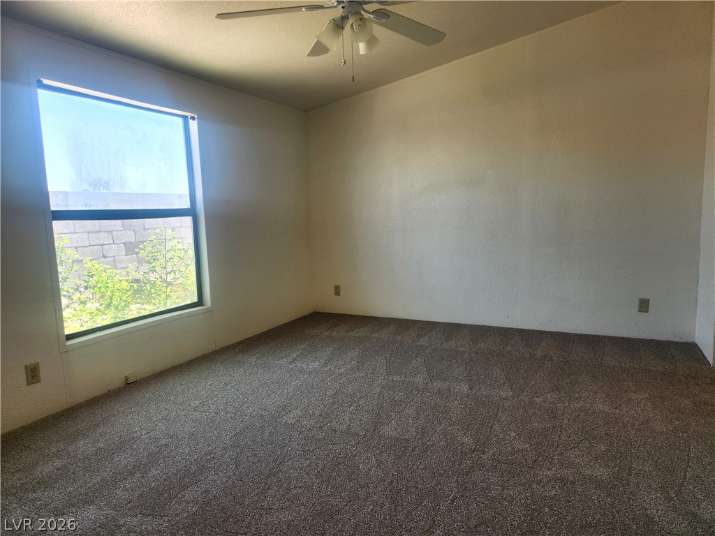 3189 Del Monte Street Laughlin, NV 89029 - Photo 13 of 32 A well-lit bedroom awaits, offering comfort and ease with plush carpeting and a cooling ceiling fan.