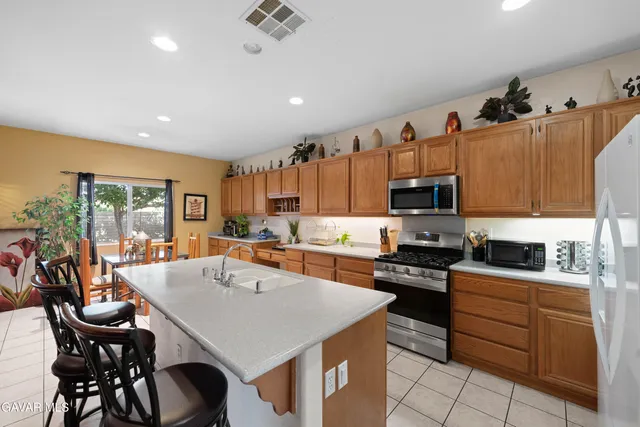 a kitchen with stainless steel appliances kitchen island granite countertop a stove a sink a dining table and chairs