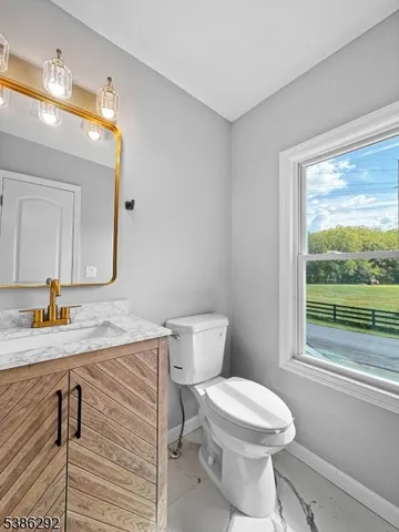 a bathroom with a granite countertop toilet a sink and a mirror