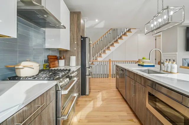 a kitchen with stainless steel appliances granite countertop a dining table chairs refrigerator and cabinets