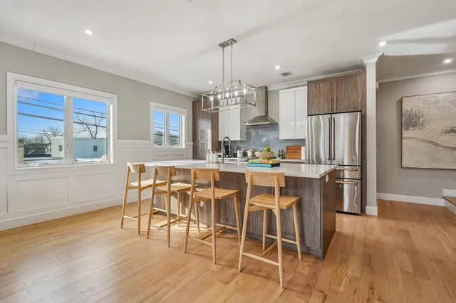 a kitchen with stainless steel appliances granite countertop a table chairs stove and wooden floor