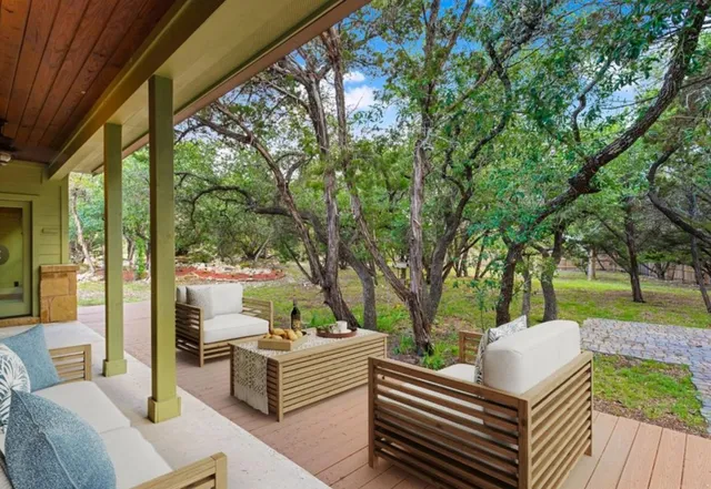 a view of a patio with couches potted plants and a large tree