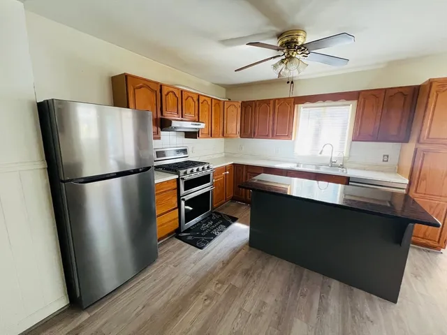 a kitchen with stainless steel appliances granite countertop a refrigerator a stove a sink and a microwave