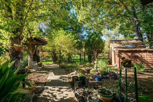 a backyard of a house with table and chairs under an umbrella