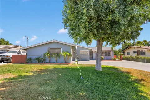 a view of a house with a yard and a large tree