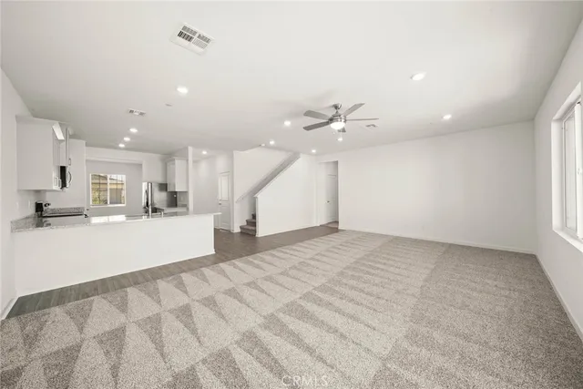 a view of an empty room and kitchen with sink