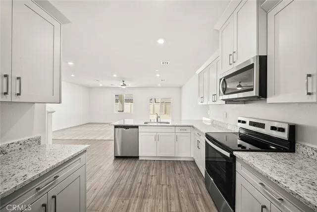 a kitchen with stainless steel appliances granite countertop wooden cabinets granite counter tops and a hard wood floors