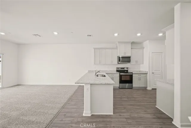 a kitchen with stainless steel appliances kitchen island granite countertop a stove a sink and a refrigerator