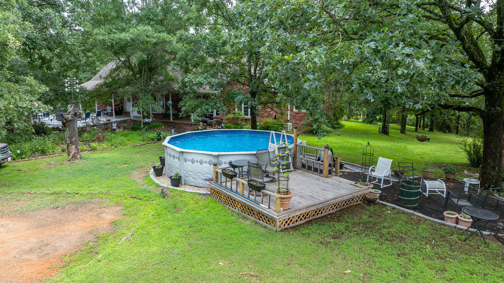 365 Calihan Road Booneville, AR 72927 - Photo 14 of 59 Expansive outdoor area featuring an above-ground swimming pool with an attached wood deck, surrounded by mature trees and a lush green lawn