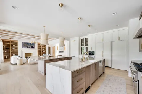 a large kitchen with kitchen island a large counter top space a sink a stove and a window