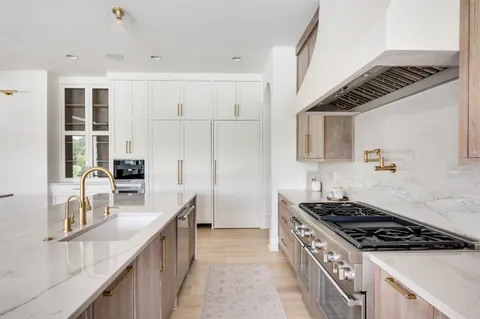 a dining hall with stainless steel appliances a sink a large window and a kitchen island