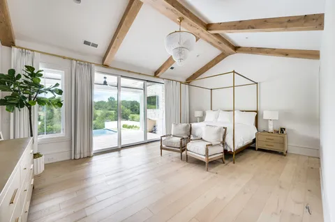 a spacious en suite bathroom with a granite countertop double vanity sink a mirror and a bathtub