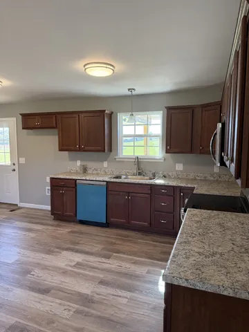 a kitchen with stainless steel appliances granite countertop a sink a stove and a wooden floors